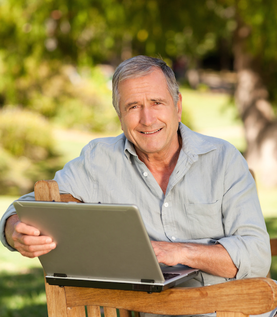 Retired man working on his laptop in the park