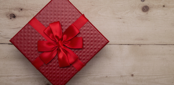 Closeup of red gift box with ribbon on vintage wooden background